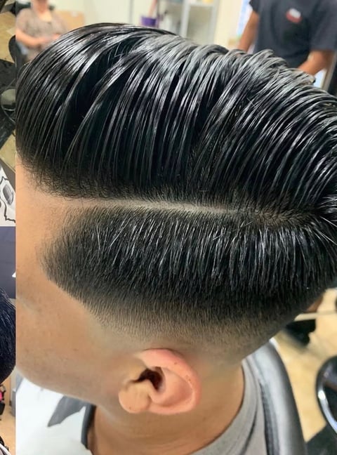Stylish mens haircut with voluminous swept-back top and sharp faded sides in a barbershop setting