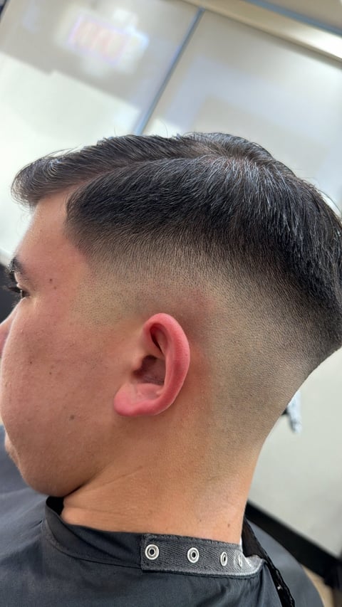 Side profile of a man with a modern fade haircut, short dark hair on top blending into closely trimmed sides