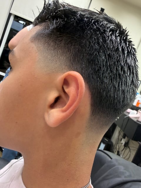 Side profile of a man with a modern fade haircut, showing short tapered sides and longer textured hair on top